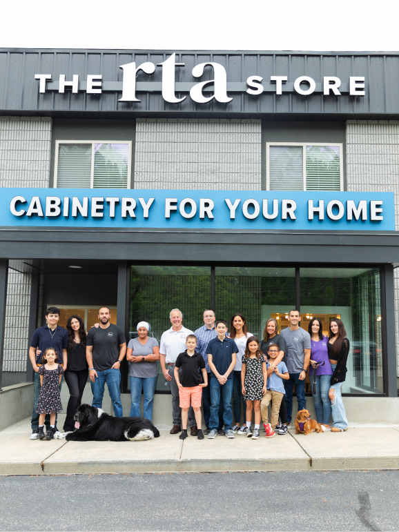 A kitchen using off-white Shaker cabinetry and barstools in front of an island.
