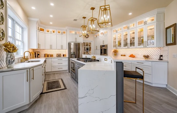 Luxurious white kitchen with marble island, gold fixtures, glass-front cabinets and modern pendant lighting—spacious, elegant design ideal for entertaining.